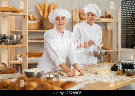 Female bakers in uniform preparing gray dough Stock Photo