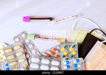 Various pills blood samples test tubes are arranged with surgical masks, use in healthcare settings during Metapneumovirus hMPV pandemic Stock Photo