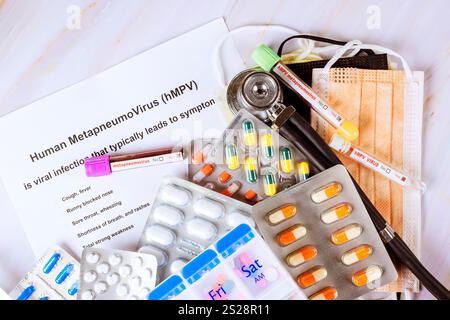 Various medications, protective masks, an informational sheet about Human Metapneumovirus hMPV are displayed on table. Stock Photo