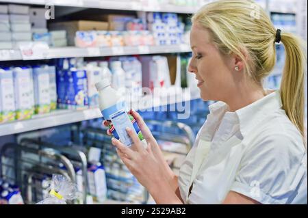 A young woman buys milk in the supermarket. Standing in front of the chiller cabinet. Austria Stock Photo