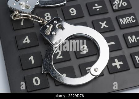 Calculator and handcuffs on a white background. Symbol photo for white-collar crime Stock Photo