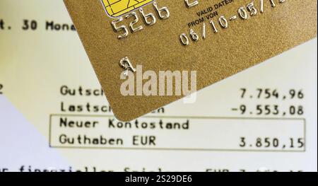 A gold credit card and bank statement... Symbolic photo for cashless shopping and status symbols. Austria Stock Photo