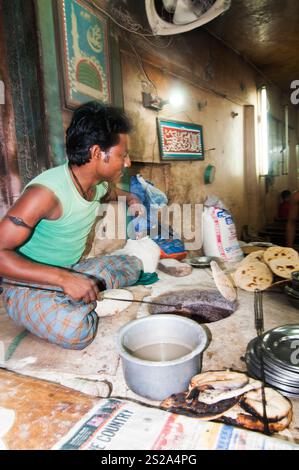 A Man baking roti breads in a tandoor oven in a small bakery at the ...