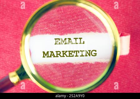 A magnifying glass highlights the phrase email marketing on a textured background, emphasizing its importance in business communication today. Stock Photo