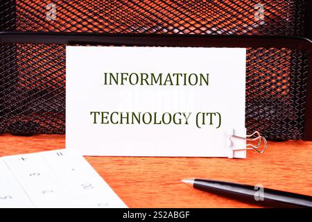 Startup office or people teamwork concept. INFORMATION TECHNOLOGY (IT) written on a white business card in close-. Stock Photo