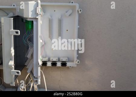 A utility box is open, revealing various networking components and wiring. The installation takes place outside a house, showcasing essential technolo Stock Photo