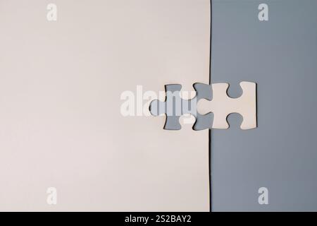 Two puzzle pieces fitting perfectly together, one on a white background and the other on a gray background. Compatibility, connection, and unity Stock Photo