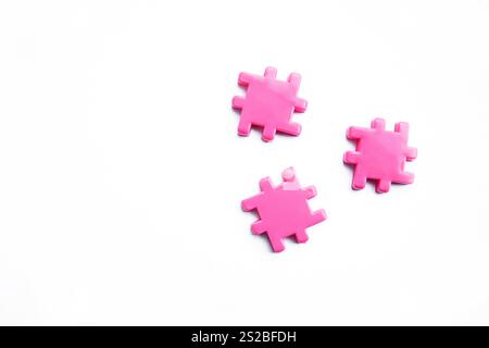 Three pink puzzle pieces placed separately on a clean white background, showcasing their vibrant color and unique shapes Stock Photo