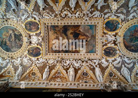 An elaborate ceiling adorned with frescoes, intricate gold detailing, and marble sculptures depicting mythological and allegorical figures in a histor Stock Photo