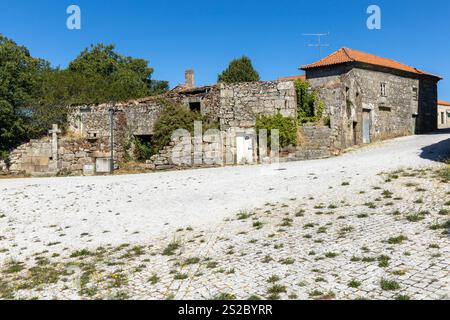 Old abandoned granite Portuguese house with religious christianity cross and blue sky Stock Photo