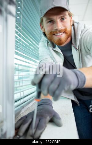 male contractor installing window blinds Stock Photo