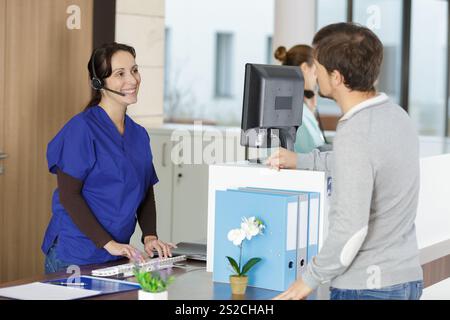 nurse talking to patient standing at reception desk in hospital Stock Photo