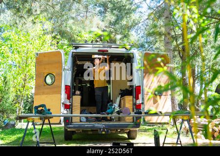 Carpenter working on campervan conversion, installing ceiling light in nature Stock Photo