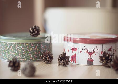 Close-up of two metal Christmas cookie tins and pinecones on a wooden table Stock Photo