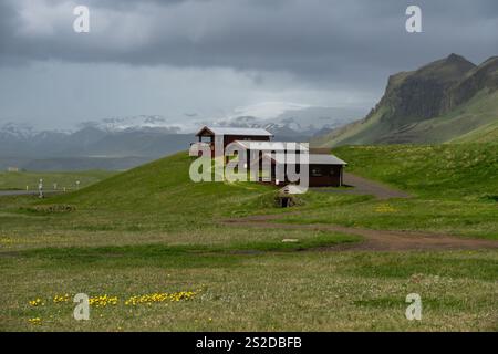 Grey sky over a Row of three traditional wooden cabins in rural landscape, Iceland Stock Photo