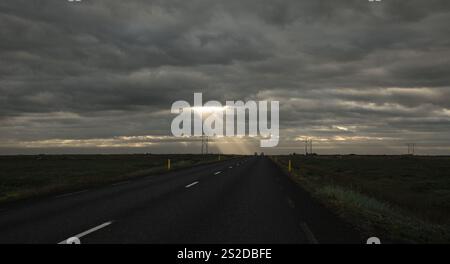 Sunlight streaming through the clouds over a country road, Iceland Stock Photo