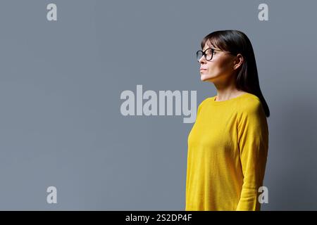 Profile view of serious middle aged woman, gray background, copy space Stock Photo