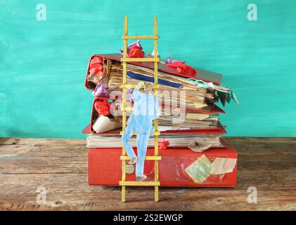 businessman climbing a stack of messy file folders,red tape, bureaucracy,beat the clock ,business concept. Stock Photo