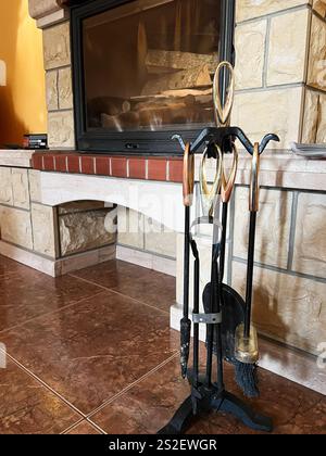 An elegant indoor fireplace with a set of fireplace tools in a warm-toned interior, showcasing a cozy and inviting atmosphere. Stock Photo
