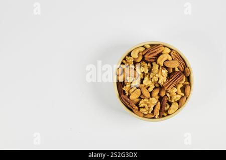 Assorted nuts in a stoneware container with a straw basket, on a white background. Almonds, Walnuts, Cashews and Chestnuts Stock Photo