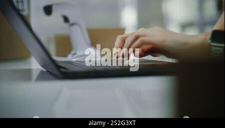 Close up of customer support specialist in logistics or post office worker processing online orders on laptop, working in warehouse retail center of postal service or E-commerce store. Slow motion. Stock Photo