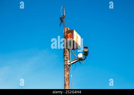 Surveillance camera and rusty corroded control box on wooden post at the street, selective focus Stock Photo