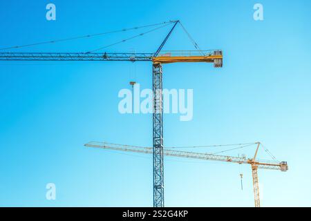 Two construction cranes against blue sky at construction site, selective focus Stock Photo