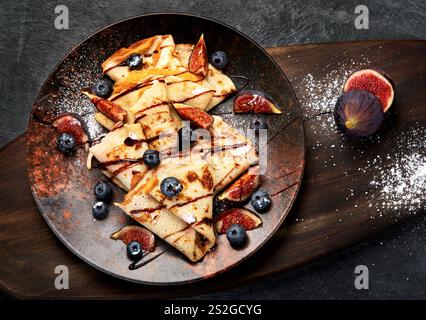 Sweet crepes with figs and chocolate on gray background. Homemade food concept. Stock Photo
