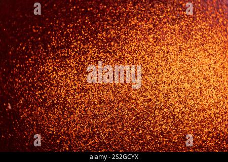 A close-up view of a shimmering orange surface, densely packed with fine glitter particles, reflecting light. Festive background. Stock Photo