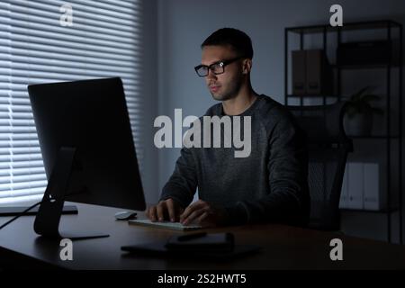 Programmer working on computer indoors at night Stock Photo