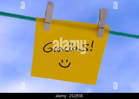 Yellow sticky note with thank you message and smiley face hanging on a clothesline Stock Photo