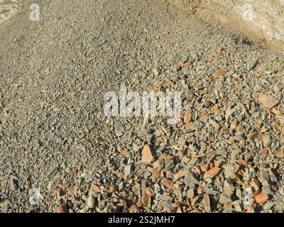 texture of small sharp stone, crumbled copper-colored rock that has rolled down a mountain in bulk, stone chips scattered on a natural slope Stock Photo