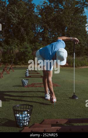 Golfer placing golf ball on tee Stock Photo