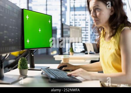 Woman testing and deploying machine learning programs and systems on isolated screen PC, solving tasks. Software engineer checking code on chroma key PC, sitting at desk in office Stock Photo