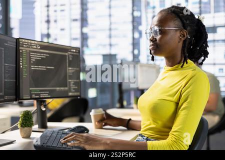 Back end developer managing cloud computing resources and platforms to train machine learning models. IT specialist monitoring and maintaining company systems, checking code on PC monitor Stock Photo