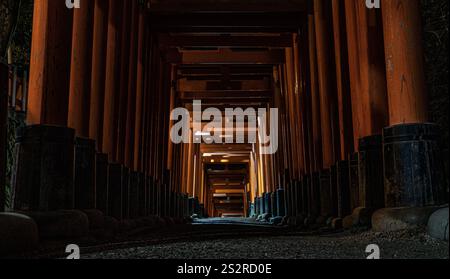 A long tunnel constructed with numerous wooden pillars leads towards a bright light shining brightly at the end of the passageway Stock Photo