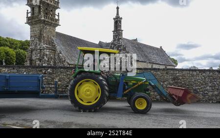 Old tractor John Deere 1040 with trailer in front of church and chapel Sainte Nonne, vintage car meeting Dirinon, department Finistere Penn ar Bed, re Stock Photo