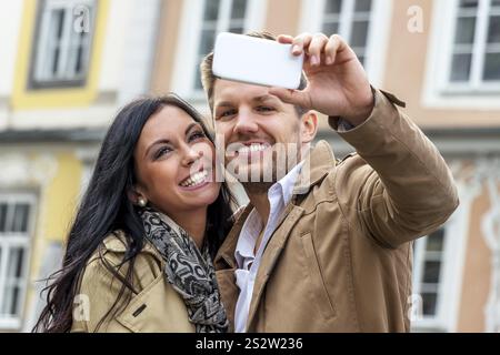 A young couple take a self-portrait with a mobile phone. Selfies are in. Austria Stock Photo