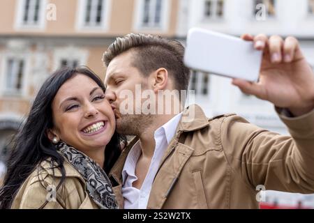 A young couple take a self-portrait with a mobile phone. Selfies are in. Austria Stock Photo