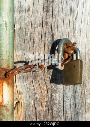 Padlock and a rusty chain securing a metal  gate keeping it closed. Stock Photo