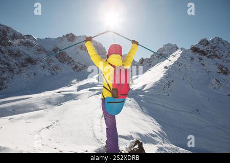 Happy Woman Raised UP Hands Holding Trekking Poles Looking To the Sun Standing with Back of Camera Stock Photo