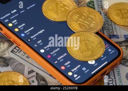 Top view of bitcoin coins lying on smartphone with cryptocurrency app on screen Stock Photo