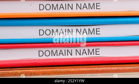 A neat stack of colorful books on technology, each labeled 'domain name,' showcases clear organization and highlights their subject matter. Stock Photo