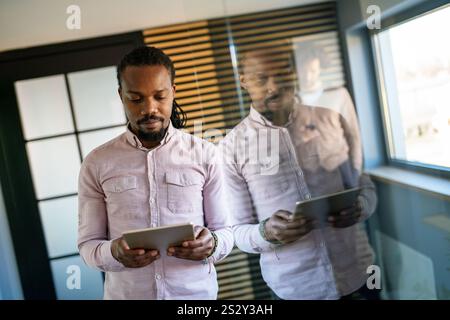 Smiling busy young African American business man, manager using tablet computer Stock Photo
