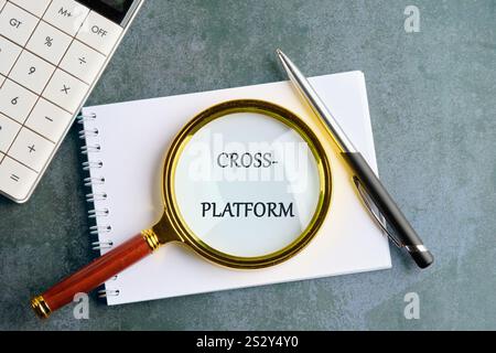 Context Marketing concept. Text CROSS-PLATFORM in a clean notebook on a gray background, top view. Stock Photo