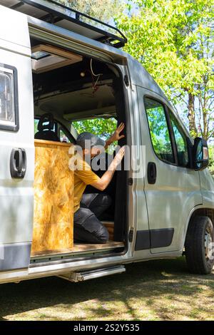 Carpenter installing mosquito net on a van door, converting a van into a camper Stock Photo