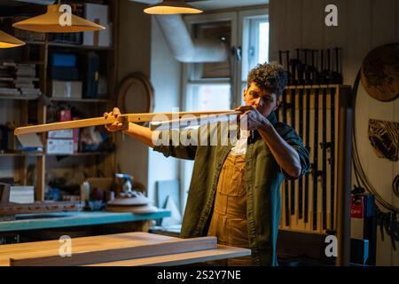 Craftsman inspects table legs and base, ensuring even surfaces and quality construction in workshop Stock Photo