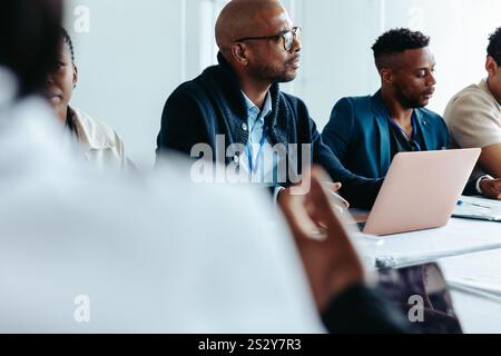 Businessmen working in a professional boardroom setting, engaged in a meeting with laptops and documents, focusing on discussions and collaboration. Stock Photo
