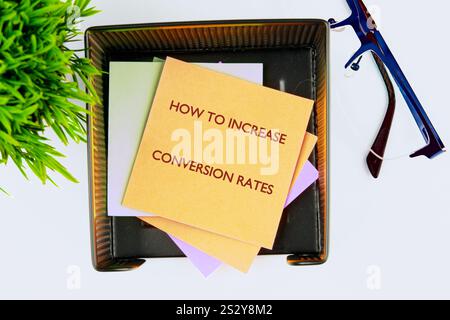 Business conversion rate optimization concept. Copy space. HOW TO INCREASE CONVERSION RATES on the yellow sticker, top view. Stock Photo
