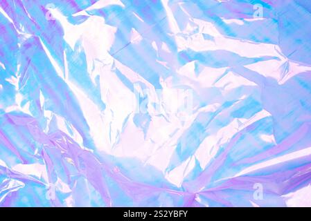 A vibrant abstract background featuring crumpled foil with a pastel gradient of pink, blue, and purple hues. Stock Photo